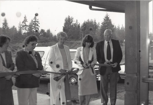 A different angle of the ribbon cutting ceremony showing five people holding the ribbon