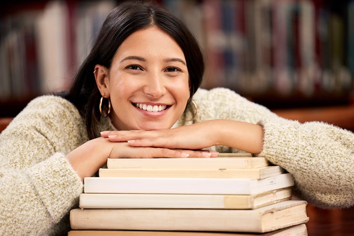 Young woman resting her chin on a pile of library books