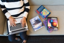 Hands on a laptop next to a pile of books