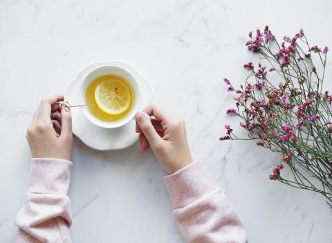 A cup of lemon tea and some purple flowers