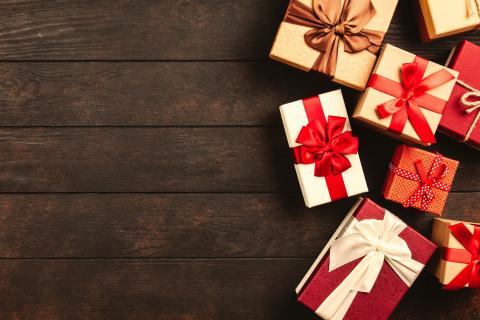 Brightly colored wrapped gifts on a dark wood surface.