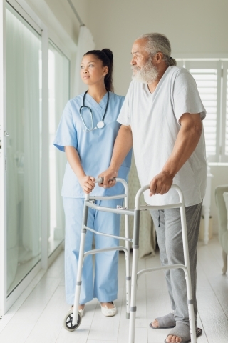 Image of a medical professional helping an older adult with a walker.