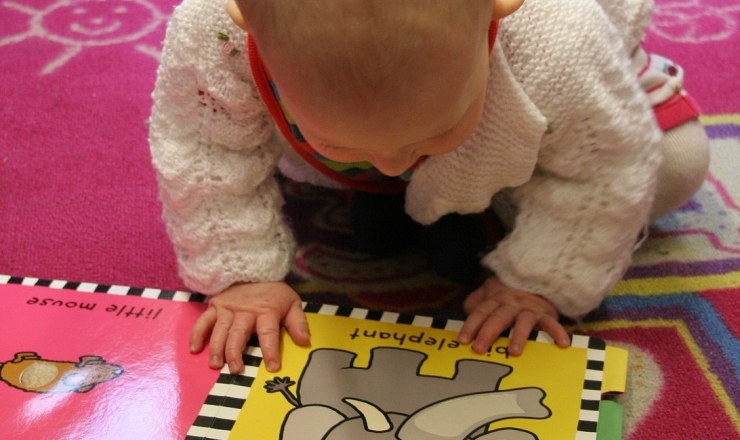 1000 Books Before Kindergarten image showing baby looking at picture book