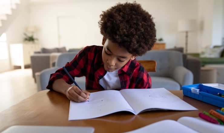 Male teen at a desk writing on paper