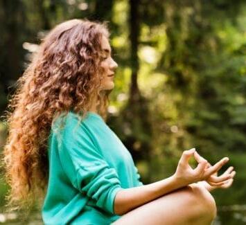 Young woman meditating in the forest